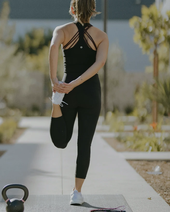 Femme en tenue de sport effectuant un étirement de la jambe pour améliorer la mobilité et la récupération