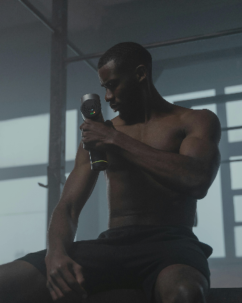 Homme utilisant un pistolet de massage pour soulager les tensions musculaires après l’entraînement