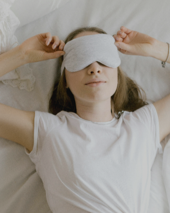 Femme allongée portant un masque de sommeil pour favoriser la détente et un sommeil réparateur